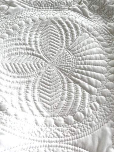 Elaborate quilting detail on white baby blanket